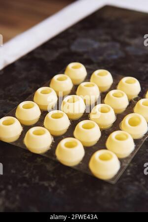 Leere kugelförmige Süßwarenformen aus weißer Schokolade auf einer Marmoroberfläche. Nahaufnahme Stockfoto