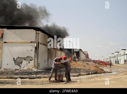 Gaza City, Gaza City. Mai 2021. Palästinenser inspizieren die Trümmer einer Fabrik nach einem israelischen Luftangriff in der Industriezone Karni östlich von Gaza-Stadt am 21. Mai 2021. Am frühen Freitag trat zwischen Israel und der Hamas ein von Ägypten vermitteltes Waffenstillstandsabkommen in Kraft, das den Gazastreifen regiert und das 11-tägige Blutvergießen beendet. Kredit: Rizek Abdeljawad/Xinhua/Alamy Live Nachrichten Stockfoto