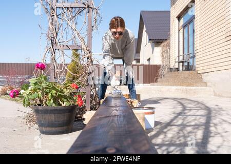 Echte Frau malt ein Brett auf der Straße. Das Leben auf dem Land. DIY Stockfoto