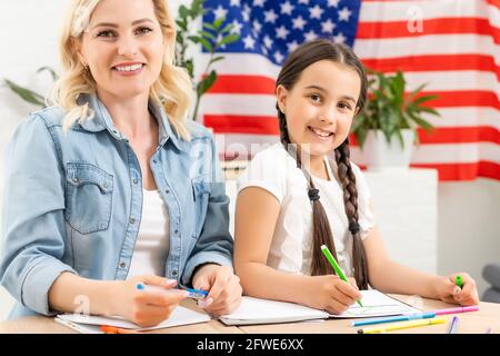 Hilfe bei den Hausaufgaben ist bei den Schülern heutzutage weit verbreitet. Englisch lernen in den USA. Englische Studentin mit der amerikanischen Flagge am Stockfoto