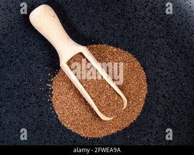 Draufsicht auf Holzschaufel auf einem Haufen voll-Korn-Teff Samen auf schwarzem Teller Stockfoto