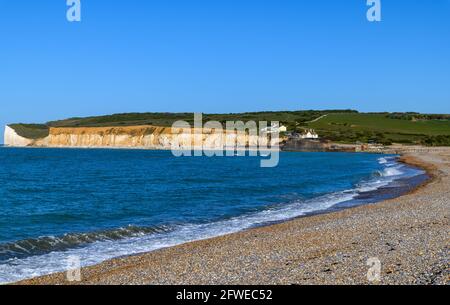 Blick über den Strand zu den Küstenschutzhütten in Cuckmere Haven, die die Hochwasserschutzmaßnahmen zeigen Stockfoto