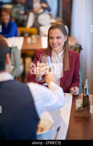 Junge, schöne kaukasische, elegante Geschäftsfrau, die im Restaurant anstößt Stockfoto
