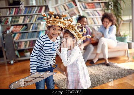 Die Kinder flüstern einige Geheimnisse, während sie zu Hause in familiärer Atmosphäre mit ihren Eltern spielen und Zeit mit ihnen verbringen. Familie, zusammen, liebe, pl Stockfoto