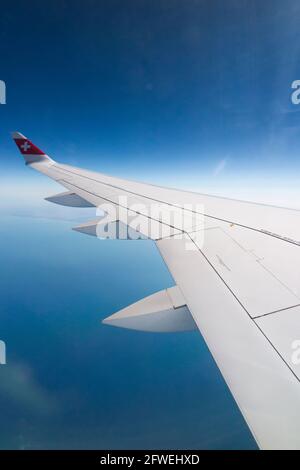 Flugzeugflügel mit Schweizer Logo-Flagge / Flugzeugflügel einer Bombardier C-Serie und Blick auf das Meer und die Küste aus seiner Reisehöhe über die Küste Frankreichs an einem klaren Tag mit blauem Himmel. (100) Stockfoto