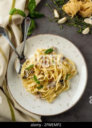 Pasta Fettuccine mit Pilzen und gebratenem Hühnerschinken in cremiger Form Käsesauce auf hellem Holzhintergrund Stockfoto