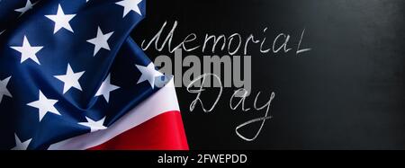 Konzept für den Memorial Day. Handgeschriebener Schriftzug auf schwarzer Tafel und amerikanischer Flagge. Denken Sie daran und ehren Sie. Stockfoto