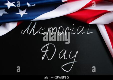 Konzept für den Memorial Day. Handgeschriebener Schriftzug auf schwarzer Tafel und amerikanischer Flagge. Denken Sie daran und ehren Sie. Stockfoto