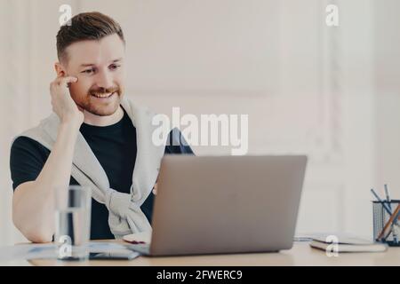 Lächelnder, männlicher Büroangestellter, der Videoanruf auf dem Laptop führt Stockfoto