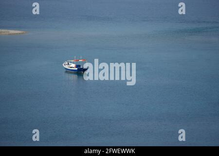 Malerische Küste mit einem isolierten griechischen Fischerboot auf den Gewässern der Insel Amorgos in den Kykladen, Griechenland. Stockfoto