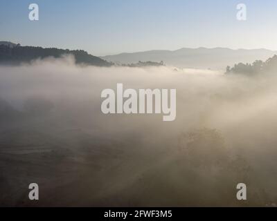 Berg in der Morgendämmerung mit Wolken, Nebelscheinstrahlen und Bäumen. Peneda Geres National Park im Morgengrauen. Stockfoto