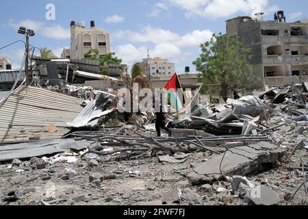 (210522) -- GAZA, 22. Mai 2021 (Xinhua) -- EIN palästinensischer Polizist der Hamas Regierung hält eine palästinensische Flagge und inspiziert die Schäden eines Regierungsgebäudes, das am 22. Mai 2021 von israelischen Luftangriffen in Gaza-Stadt angegriffen wurde. (Foto von Rizek Abdeljawad/Xinhua) Stockfoto