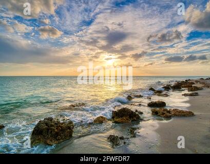 Felsige Küste von Caspersen Beach in Venedig Florida USA mit Ein gelb-oranger Sonnenuntergang über dem Golf von Mexiko Stockfoto