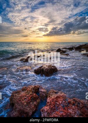 Felsige Küste von Caspersen Beach in Venedig Florida USA mit Ein gelb-oranger Sonnenuntergang über dem Golf von Mexiko Stockfoto