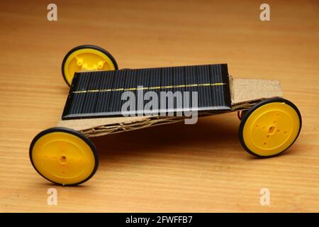 Future Concept Solarauto mit Vorderradantrieb. Kleines Arbeitsmodell des Solarautos, das von Solarpanel auf hölzernen Hintergrund angetrieben wird Stockfoto