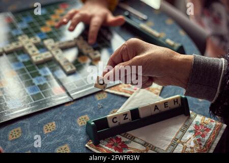 Reife Hände mit Arthritis, spielen Buchstaben Spiel Stockfoto