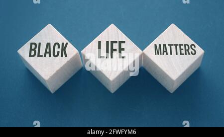 Text von BLM bedeutet, dass Black Lives Matter auf Holzblöcken auf schwarzem Hintergrund geschrieben ist. Stockfoto