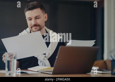 Fokussierter Geschäftsmann, der von zu Hause aus arbeitet und Dokumente ansieht Stockfoto