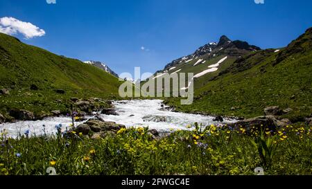 Spektakuläre Aussicht auf die verschneiten Berge und das Tal, die den Frühling zeigen. Stockfoto