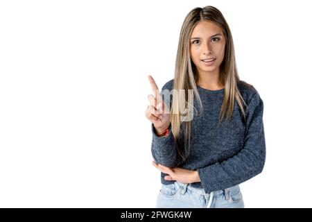 Attraktive Latina-Frau mit neutralem Ausdruck, die mit ihrem Zeigefinger ein Zeichen auf einem rein weißen Hintergrund macht. Stockfoto