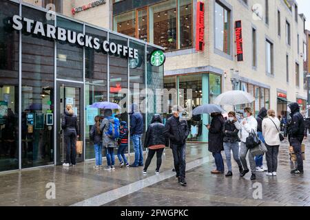 Münster, NRW, Deutschland. Mai 2021. In einem Starbucks-Café kann man sich anstehen. In der Altstadt von Münster versammeln sich trotz heftigem Regen Menschenmassen, denn es wird die erste Stadt in Nordrhein-Westfalen, in der es möglich ist, Indoor-Trink- und Gastronomiebereiche (mit negativem Test oder Impfung) und Shopping ohne Test oder Termin (aber die Anzahl ist begrenzt) zu eröffnen. Münster hat derzeit mit 17/100k eine der niedrigsten covid-Inzidenzraten in NRW und hat sich zu einer „Modellregion“ entwickelt, um eine langsame Wiedereröffnung von Hospitality-Locations zu testen. Kredit: Imageplotter/Alamy Live Nachrichten Stockfoto