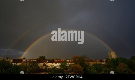 Wimbledon, London, Großbritannien. 22 Mai 2021. Der heftige Abendregen endet mit einem hellen doppelten Regenbogen über den Häusern in einem Vorort Londons. Quelle: Malcolm Park/Alamy Live News. Stockfoto