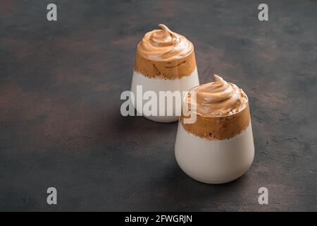 Kaffee-Dessert mit Milch in zwei Gläsern auf braunem Hintergrund. Seitenansicht, Kopierbereich. Stockfoto