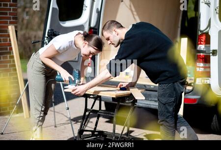 03. April 2021, Niedersachsen, Großenmeer: Greta Thomas und Hannes Wehrmann sägen Holz vor ihrem Mercedes-Benz Sprinter, den das Paar mit eigener Arbeit in einen Wohnmobil umwandelt. Foto: Hauke-Christian Dittrich/dpa Stockfoto