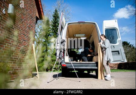 03. April 2021, Niedersachsen, Großenmeer: Greta Thomas und Hannes Wehrmann arbeiten an ihrem Mercedes-Benz Sprinter, den das Paar mit eigenen Händen in einen Wohnmobil umbaute. Ferien mit einem selbst gebauten Wohnmobil sind im Trend - die Umsetzung wird oft ausführlich für YouTube oder Instagram dokumentiert. Foto: Hauke-Christian Dittrich/dpa Stockfoto