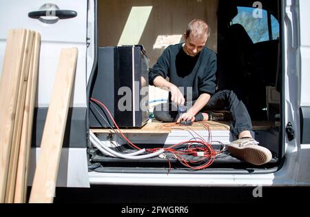 03. April 2021, Niedersachsen, Großenmeer: Hannes Wehrmann installiert die elektrischen Komponenten in seinem Mercedes-Benz Sprinter, den er zusammen mit seiner Freundin Greta Thomas in einen Wohnmobil umwandelt. Foto: Hauke-Christian Dittrich/dpa Stockfoto