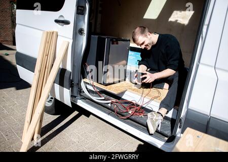 03. April 2021, Niedersachsen, Großenmeer: Hannes Wehrmann installiert die elektrischen Komponenten in seinem Mercedes-Benz Sprinter, den er zusammen mit seiner Freundin Greta Thomas in einen Wohnmobil umwandelt. Foto: Hauke-Christian Dittrich/dpa Stockfoto