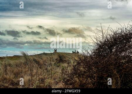 Dunstanburgh Castle auf einem entfernten Hügel Stockfoto