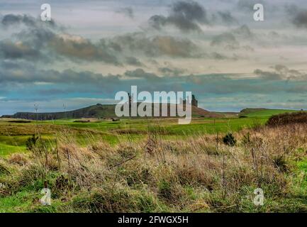 Dunstanburgh Castle auf einem entfernten Hügel Stockfoto