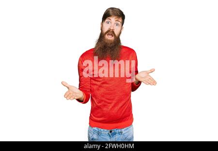 Rotschopf Mann mit langen Bart tragen lässige Kleidung ahnungslos und verwirrt Ausdruck mit Armen und Händen angehoben. Zweifel Konzept. Stockfoto