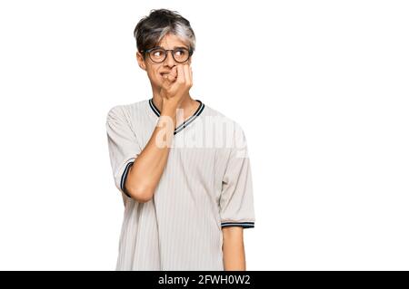 Junge hispanische Mann trägt Freizeitkleidung und Brille gestresst und nervös mit Händen auf Mund beißen Nägel. Angst Problem. Stockfoto