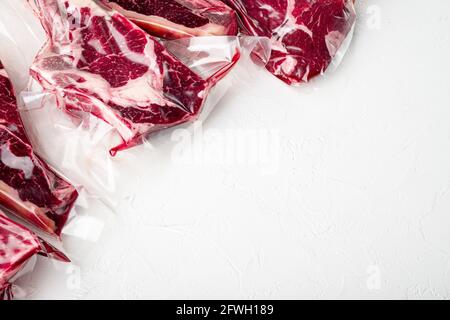 Frische, leckere rohe Rindersteaks mit Knochen, verpackt in Vakuum-Plastikverpackung am Marktset, Tomahawk, T-Bone, Clubsteak, Rib-Eye- und Filet-Schnitten, auf w Stockfoto