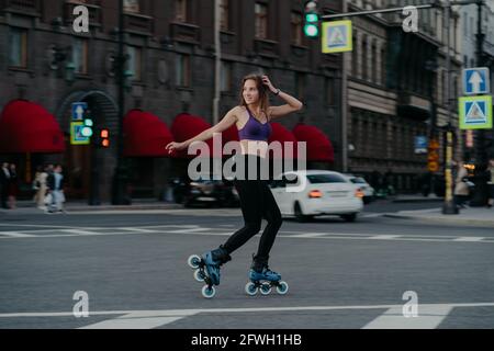 SIM Woman reitet auf Rollerblades loks weg trainiert verschiedene Muskeln Gruppen von Beinen und Kern entwickelt Ausdauer verwaltet ihr Gewicht Verbrennt Kalorien Stockfoto