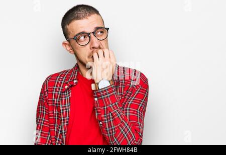 Hispanic junger Mann trägt lässige Kleidung, die gestresst und nervös mit den Händen auf den Mund beißen Nägel. Angst Problem. Stockfoto