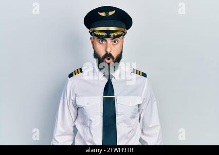 Junger hispanischer Mann in Flugzeugpilotenuniform, ängstlich und schockiert mit überraschenden Gesichtsausdruck, Angst und aufgeregt. Stockfoto