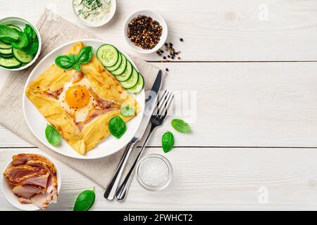 Bretonischer Pfannkuchen mit Ei, Schinkenkäse, Gurke und Basilikum auf weißem Hintergrund. Stockfoto