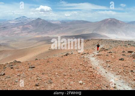 Kletterer bestiegt den Vulkan Siete Hermanos über der Laguna Santa Rosa in der Atacama-Wüste (Chile), einer der unwirtlichsten Regionen der Erde Stockfoto
