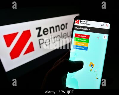 Person, die Mobiltelefon mit der Webseite des britischen Öl- und Gasunternehmens Zennor Petroleum Ltd. Auf dem Bildschirm mit Logo hält. Konzentrieren Sie sich auf die Mitte des Telefondisplays. Stockfoto