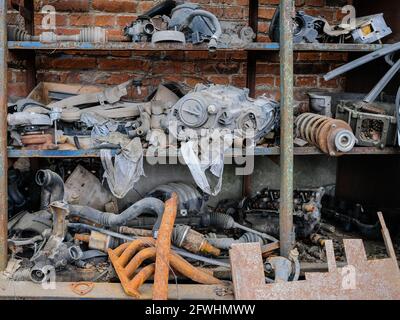 Alte rostige Autoteile stapelten sich auf einem Regal vor einem Backsteinwand-Hintergrund. Müll nach Autoreparaturen. Grunge. Stockfoto