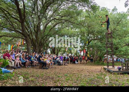 Ichabod Wainwright jongliert mit flammenden Äxten und steht auf gestapelten Stühlen beim Bay Area Renaissance Festival, Withlacoochee River Park, Dade City, Florida Stockfoto