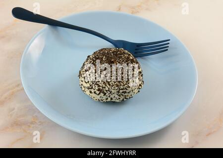 Kokos- und Kaffee-Schneeballkuchen auf blauem Dessertteller mit Blaue Gabel Stockfoto