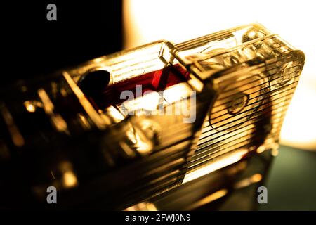 Sepia-getönte Makroaufnahme von rotem Klebeband und Pinch Roller Der vor hellem Licht isolierten Durchsicht-Kassette Auf schwarzem und grünem Hintergrund Stockfoto