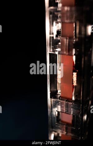 Makroansicht des roten Bands auf der Unterseite der vertikalen Kassette Isoliert auf schwarzem Hintergrund Stockfoto