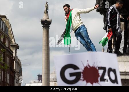 London, Großbritannien. 22. Mai 2021. Ein Mann steht auf dem Sockel einer Statue, als Zehntausende von Menschen sich während der Nationalen Demonstration für Palästina dem Trafalgar Square nähern. Sie wurde von pro-palästinensischen Solidaritätsgruppen organisiert, um gegen die jüngsten Angriffe Israels auf Gaza, seine Angriffe auf die Al-Aqsa Moschee und seine Versuche, palästinensische Familien aus dem Sheikh Jarrah-Viertel in Ostjerusalem gewaltsam zu vertreiben, zu protestieren. Kredit: Mark Kerrison/Alamy Live Nachrichten Stockfoto