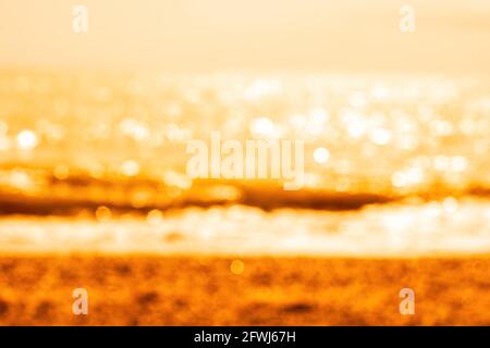 Abstrakte Natur Sommer oder Frühling Meer Meer Hintergrund. Kleine Wellen auf der goldenen, warmen Wasseroberfläche verwischen sich in Bewegung mit Bokeh-Lichtern vom Sonnenuntergang. Urlaub Stockfoto