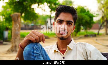 Porträt eines gesunden jungen Mannes, der im Park sitzt und die Kamera anschaut. Stockfoto